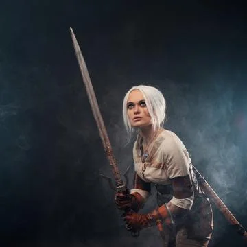A young warrior with a sword on a dark background. Fantasy heroine Stock Photos