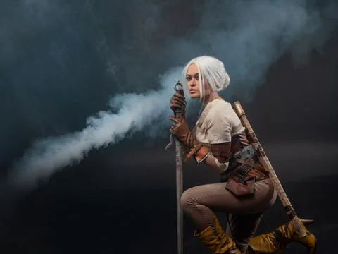 A young warrior with a sword on a dark background. Fantasy heroine Stock Photos