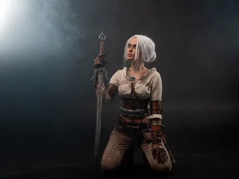 A young warrior with a sword on a dark background. Fantasy heroine Stock Photos