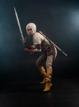 A young warrior with a sword on a dark background. Fantasy heroine Stock Photos