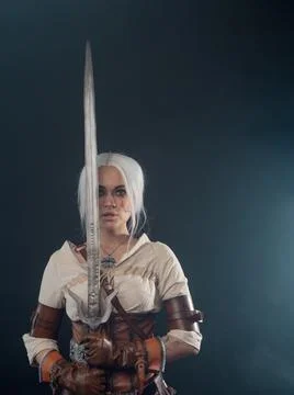 A young warrior with a sword on a dark background. Fantasy heroine Foto stock