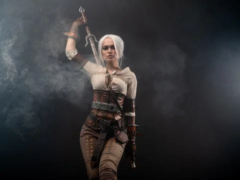 A young warrior with a sword on a dark background. Fantasy heroine Foto stock