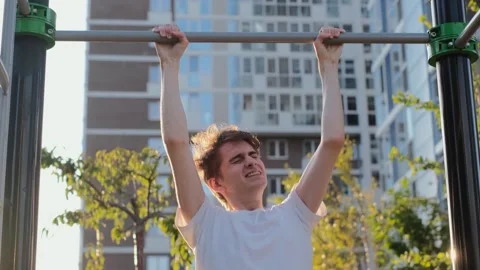 A young weak guy cannot do pull-ups on the horizontal bar Stock Footage 280508759