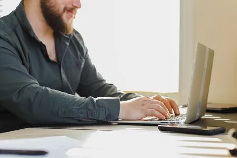 Young web developer working with laptop in office, sitting at desk. Stock Photos