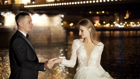 Young wedding couple, bride and groom in white dress, dancing, holding hands, hu Stock Footage 129690969
