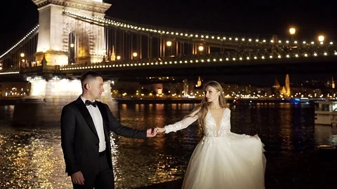 Young wedding couple, bride and groom in white dress, dancing, holding hands Stock Footage 129690976