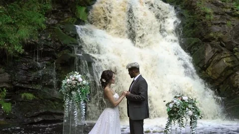 Young wedding couple at ceremony near waterfall Stock Footage
