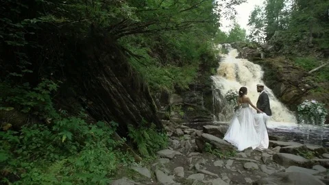 Young wedding couple at ceremony near waterfall Stock Footage