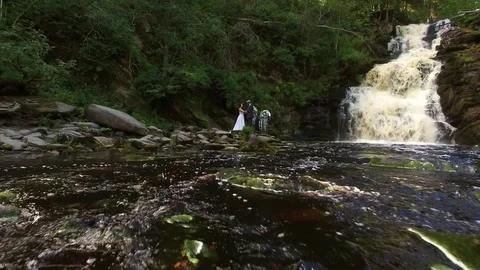 Young wedding couple walking near waterfall Stock Footage