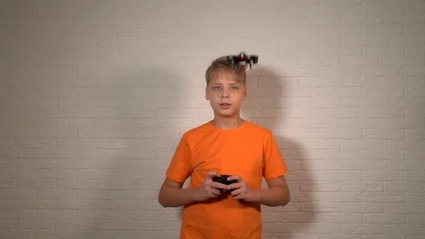 Young white boy operating small toy drone using remote control Stock Footage 127752175