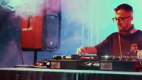 A young white Caucasian man performing as a DJ with smoke and strobe lights Stock Footage 247394085