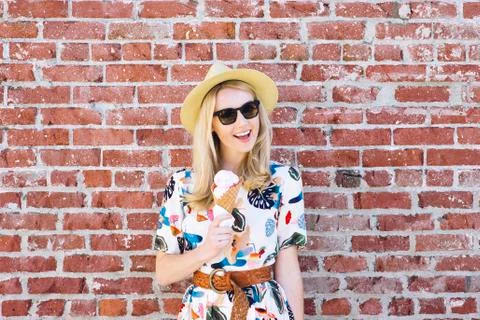 Young white female eats an ice cream cone on a summer day with sunglasses and Stock Photos