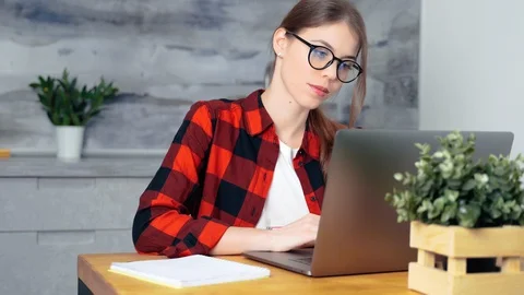 A young white female student working hard using a laptop preparing for some e Stock Footage