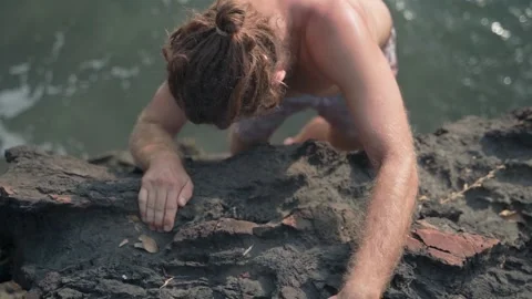 A young white guy with bare breasts climbs the rock with tension. Video stock 234021820