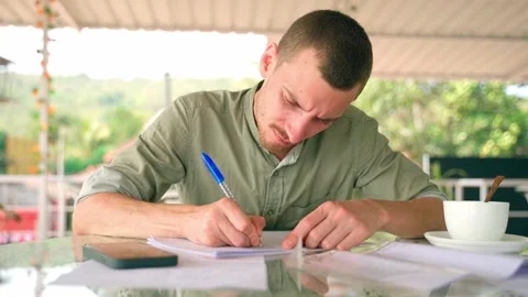 A young white guy carefully writing in a notebook, high quality. Video stock 231336682