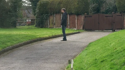 Young white man in hooded jacket walks with labradoodle dog towards camera Stock Footage 87981523