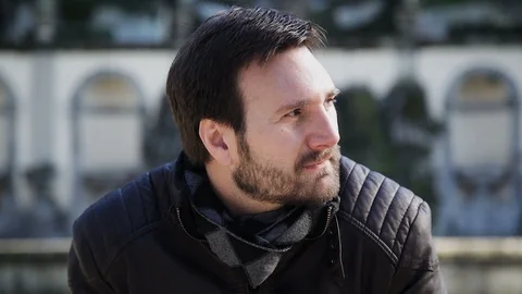 A young white man looks at the camera with a smile and looks around Stock Footage 102281483