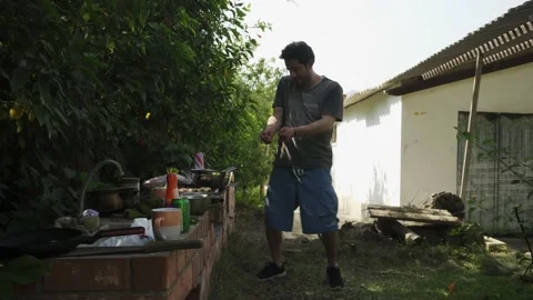 A young white man preparing a barbecue dancing and drinking beer in a country Video stock 170017239