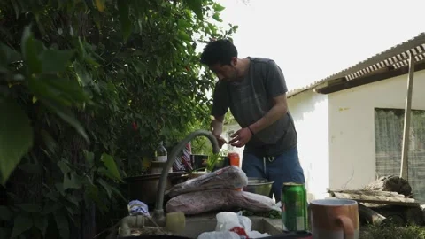 A young white man preparing a grill in a country house with vegetation in the Stock Footage 170017168
