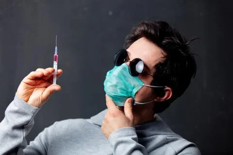 Young white man in protective mask and sunglasses with syringe vaccine Stock Photos