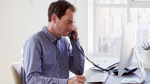 Young white man using phone and computer in an office Stock Footage 78937663