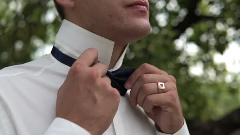 A young white man wears a black bow tie. The groom puts on a suit on the street. Stock Footage 163095157