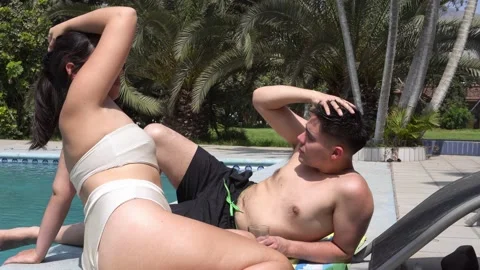 A young white-skinned couple lying beside a pool in a country house in bathing Video stock 161941304