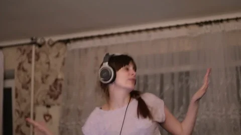 A young white woman is dancing while listening to headphones. A woman enjoys Stock Footage 82631037