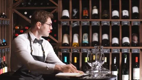 Young wine critic makes notes in his notebook about the quality and sediment of Stock Photos