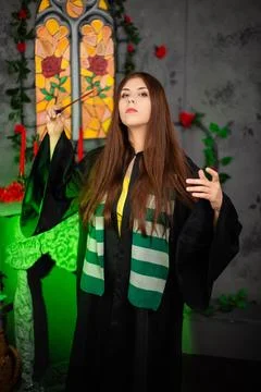 A young witch in a black cloak with a magic wand in her hands conjures a spell Stock Photos