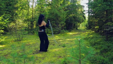 A young witch in black clothes, released from chains, dances with them in the Stock Footage 96262179