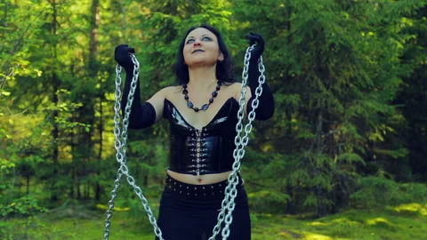 A young witch in black clothes, released from chains, dances with them in the Stock Footage 96306362