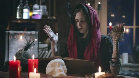 Young witch casting spell with closed eyes using snake and book Stock Footage 136881775