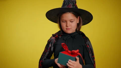 A Young Witch Excitedly Unwrapping a Special Gift on a Vibrant Bright Yellow Stock Footage 315411853