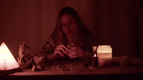 Young witch fortune teller reads tarot cards by candlelight Stock Footage 305822337