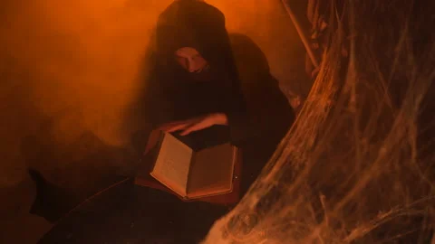 A young witch in hood does black magic ritual using the Witch's book. Halloween 스톡 동영상 163389215