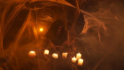 A young witch in hood does black magic ritual using the Witch's book. Halloween Stock Footage 163389361