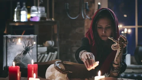 Young witch performing magical ritual using candle and snake Stock Footage 136890079