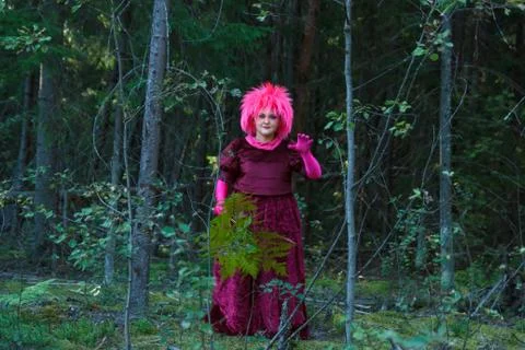 A young witch in purple clothes performs a magical ritual with a fern in the Fotos Stock