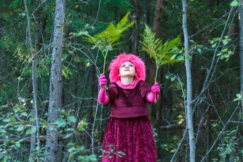 A young witch in purple clothes performs a magical ritual with a fern in the Stock Photos