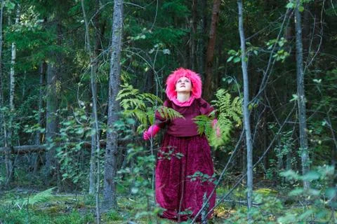 A young witch in purple clothes performs a magical ritual with a fern in the Stock Photos