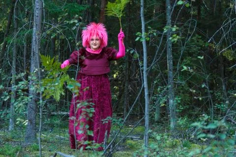 A young witch in purple clothes performs a magical ritual with a fern in the 스톡 사진