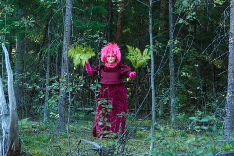 A young witch in purple clothes performs a magical ritual with a fern in the 写真素材