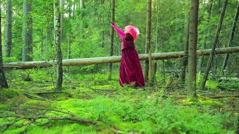 A young witch in red in the forest will twist his staff over his head. 스톡 동영상 95146533