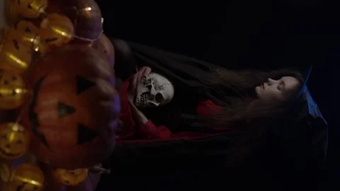 Young witch with skull and pumpkins Stock Footage 140859722