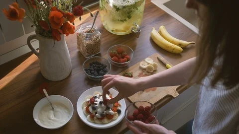 Young woman adding freshly picked raspberry on muesli meal Stock Footage 96241925