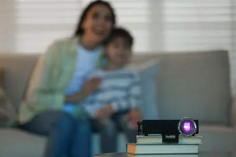 Young woman and her son watching movie at home, focus on video projector Stock Photos