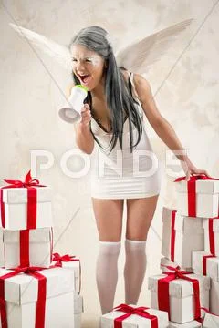 Young woman as angel with heap of gift boxes shouting through megaphone Stock Photos