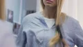 Young woman annoyed by dry bleached hair, combing angrily, vitamin deficiency HD Footage