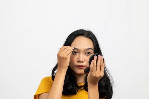 Young Woman Applying Makeup While Looking Into Handheld Mirror with Natural.. Stock Photos